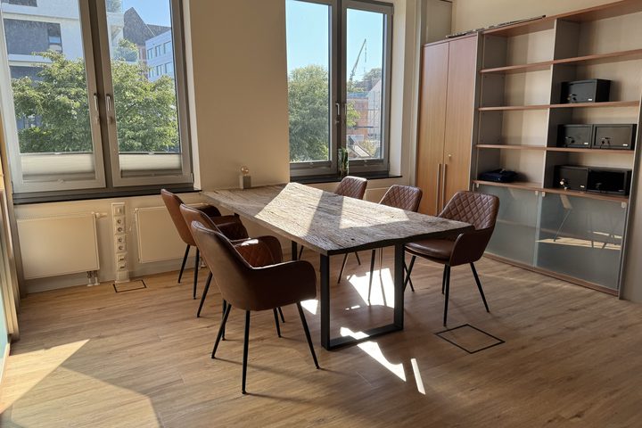 Großer Holztisch mit Lederstühlen vor einer Regalwand