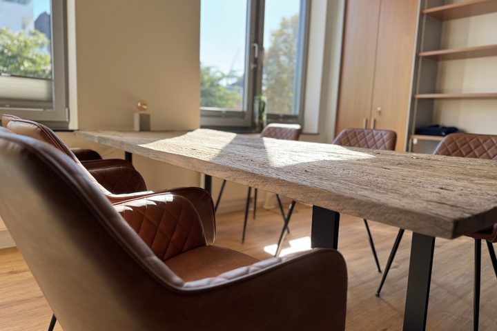Besprechungstisch aus Holz mit Ledersessel am Fenster