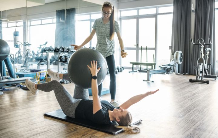 Therapeutin leitet eine Frau bei einer Übung mit dem Gymnastikball an